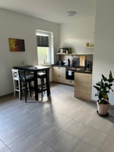 Hellbraune Küchenzeile der Ferienwohnung mit Bartisch und Barstühlen