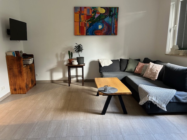 Wohnbereich der Ferienwohnung mit einem grauen Sofa, dem braunen Couchtisch und einem Smart Tv