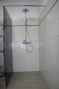 Großer, ebenerdiger Duschbereich mit braunen Fliesen und Regendusche